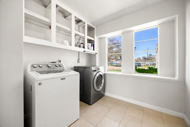 clothes washing area featuring washing machine and clothes dryer and light tile patterned floors