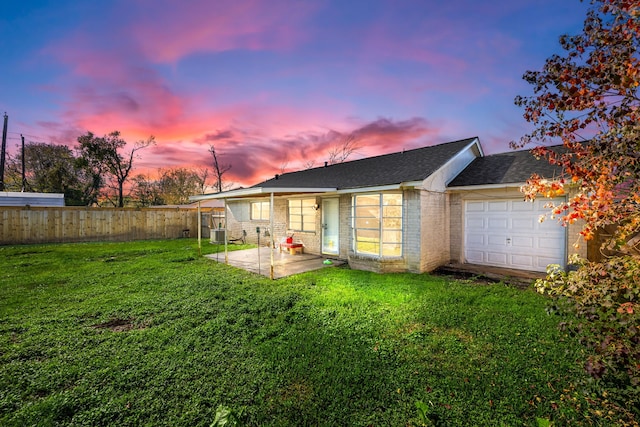 back house at dusk with a garage, a patio area, and a yard