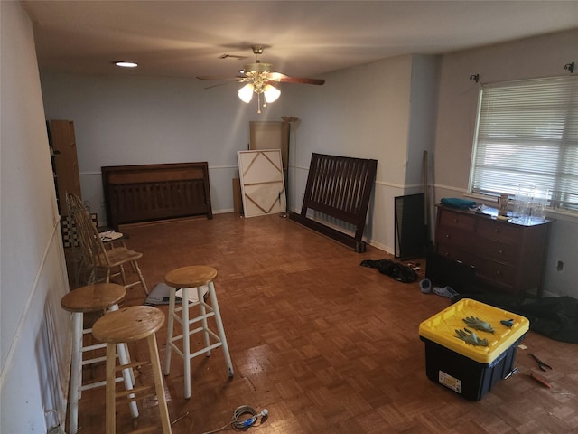 living area featuring dark parquet floors and ceiling fan