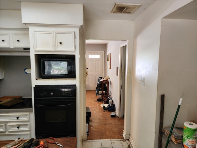 kitchen featuring black appliances, white cabinetry, and light tile patterned floors