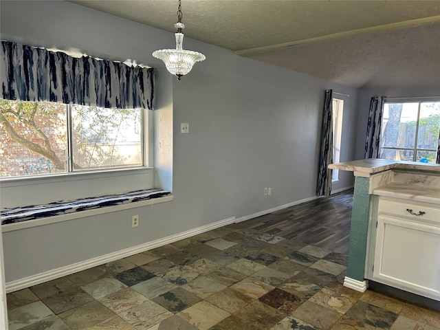 unfurnished dining area featuring a textured ceiling and a notable chandelier