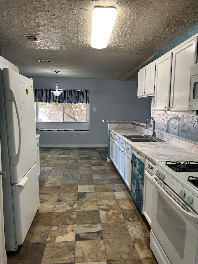 kitchen with a textured ceiling, white appliances, sink, white cabinets, and hanging light fixtures