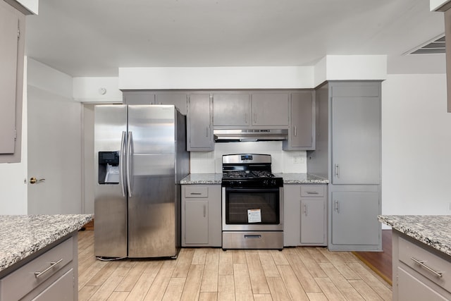 kitchen with gray cabinetry, light hardwood / wood-style floors, light stone countertops, and appliances with stainless steel finishes