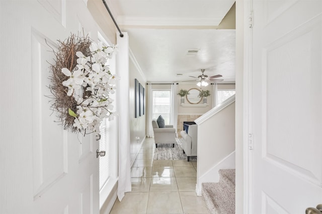 tiled foyer entrance featuring a tiled fireplace, ceiling fan, and crown molding