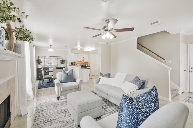 tiled living room featuring a high end fireplace, ceiling fan, and crown molding