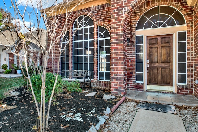 doorway to property featuring a porch and brick siding