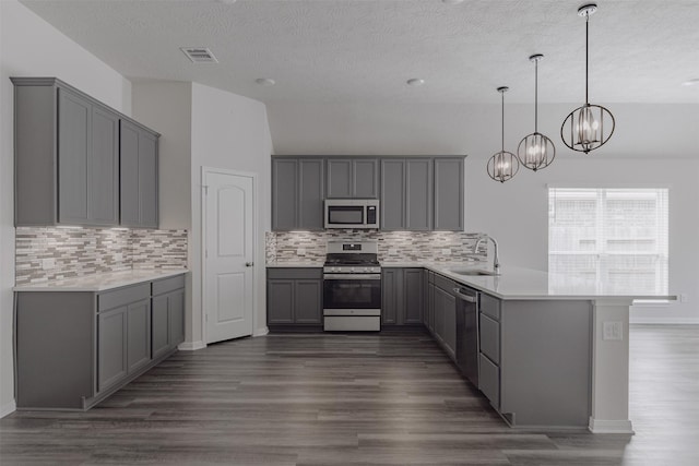 kitchen with gray cabinets, kitchen peninsula, stainless steel appliances, and decorative light fixtures