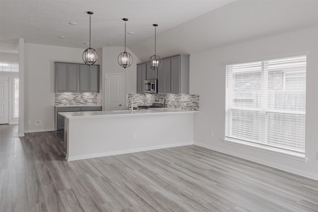 kitchen with kitchen peninsula, backsplash, stainless steel appliances, and lofted ceiling