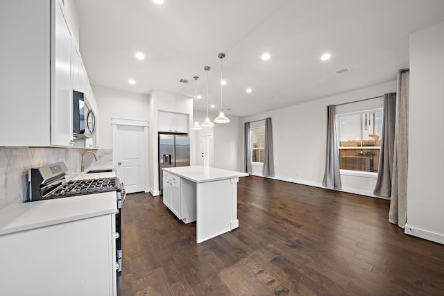 kitchen with white gas stove, a kitchen island, white cabinetry, and hanging light fixtures