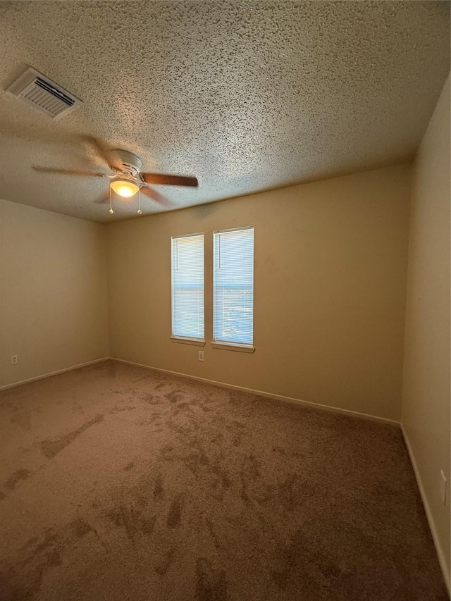 carpeted empty room with ceiling fan and a textured ceiling