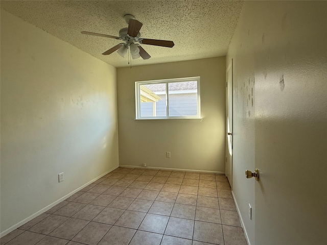 tiled empty room featuring ceiling fan and a textured ceiling