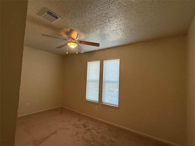 carpeted spare room featuring a textured ceiling and ceiling fan