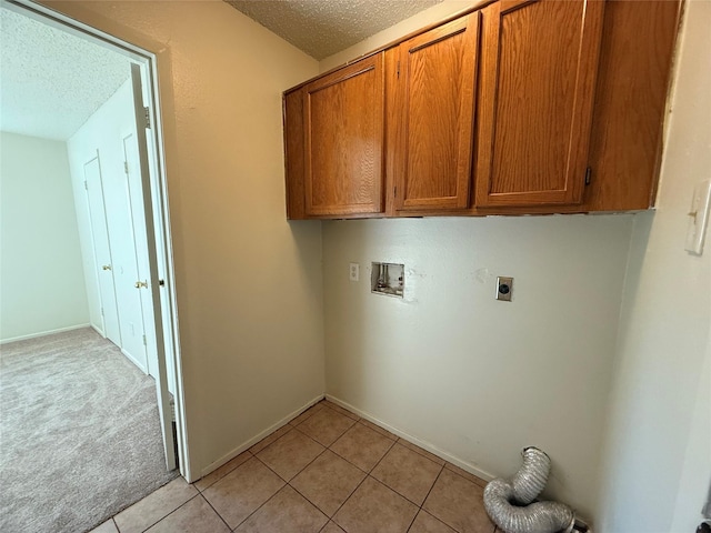 washroom with cabinets, washer hookup, a textured ceiling, hookup for an electric dryer, and light tile patterned flooring