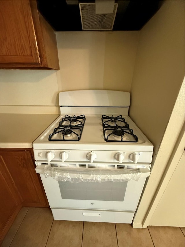 kitchen with gas range gas stove, light tile patterned flooring, and exhaust hood