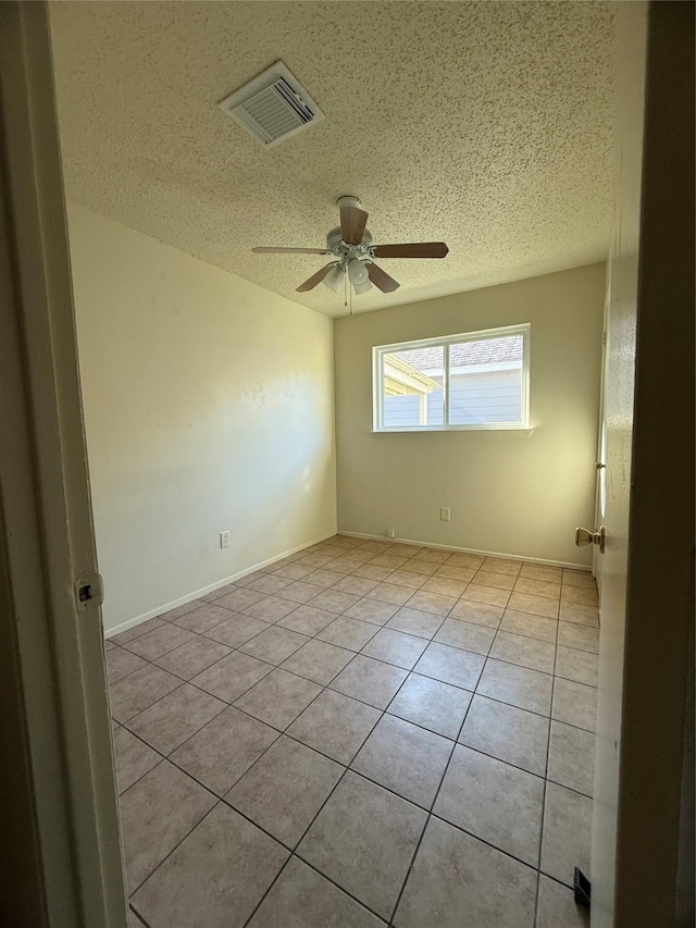 tiled empty room featuring ceiling fan and a textured ceiling