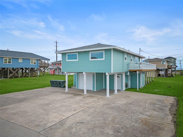 back of house featuring a garage, a deck, and a lawn