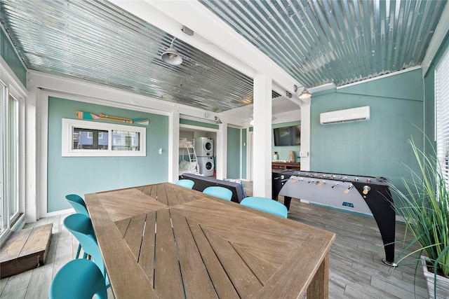 exterior space featuring a wealth of natural light, a wall mounted air conditioner, and stacked washer and clothes dryer