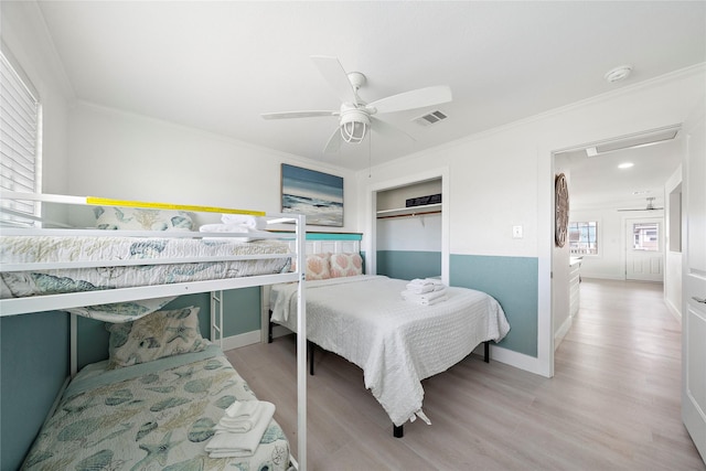 bedroom featuring light wood-type flooring, a closet, ceiling fan, and crown molding