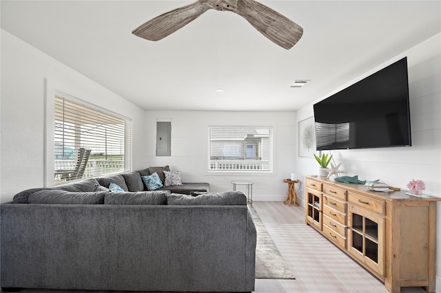 living room with electric panel, ceiling fan, and light wood-type flooring