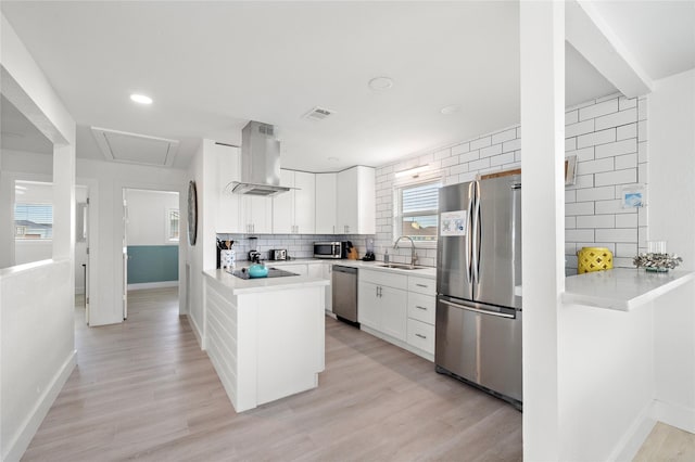 kitchen featuring stainless steel appliances, white cabinetry, tasteful backsplash, and wall chimney exhaust hood