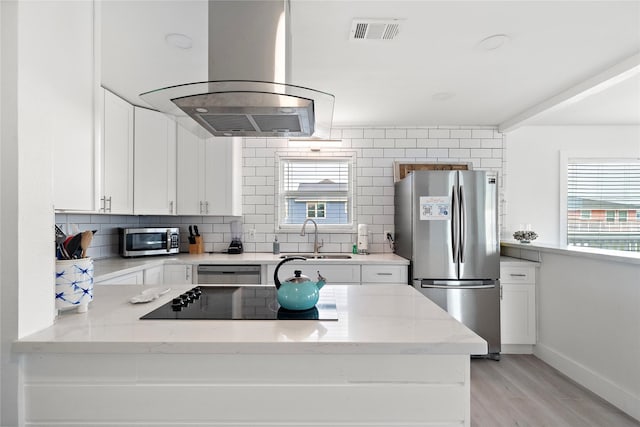 kitchen featuring light stone countertops, island exhaust hood, stainless steel appliances, sink, and white cabinets