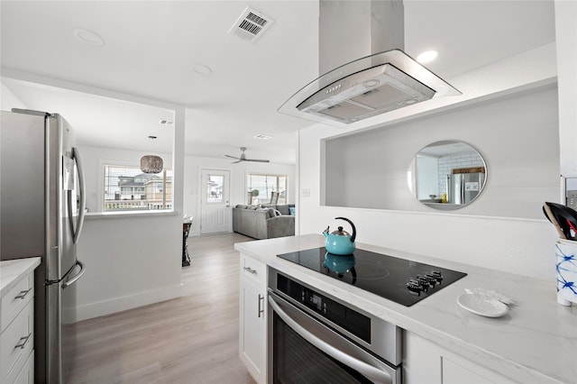 kitchen featuring light stone countertops, a wealth of natural light, stainless steel appliances, ceiling fan, and white cabinets