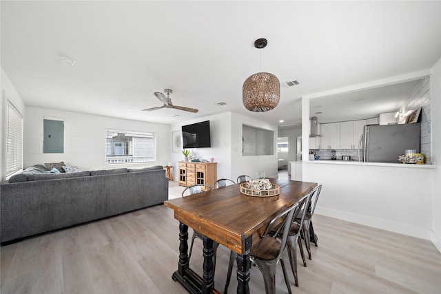 dining room with electric panel, ceiling fan, and light wood-type flooring