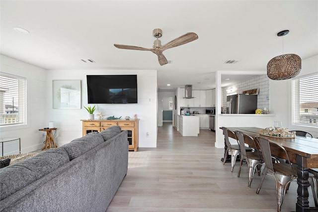 living room with ceiling fan, plenty of natural light, and light hardwood / wood-style flooring