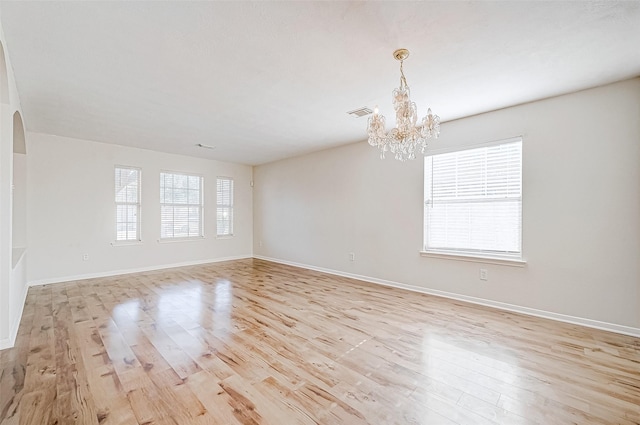 unfurnished room with light hardwood / wood-style floors and a notable chandelier