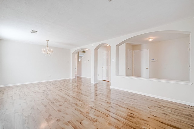 empty room with light hardwood / wood-style flooring and an inviting chandelier