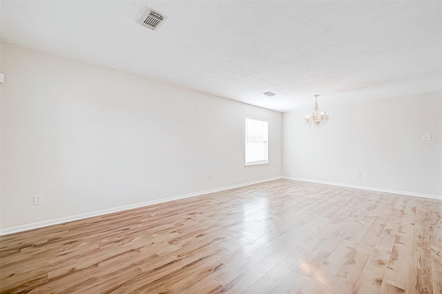 spare room featuring light hardwood / wood-style flooring and an inviting chandelier