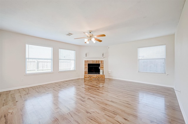 unfurnished living room with ceiling fan, light hardwood / wood-style floors, and a brick fireplace