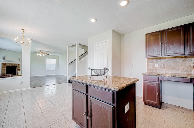 kitchen featuring ceiling fan with notable chandelier, a kitchen island, decorative backsplash, and light tile patterned floors