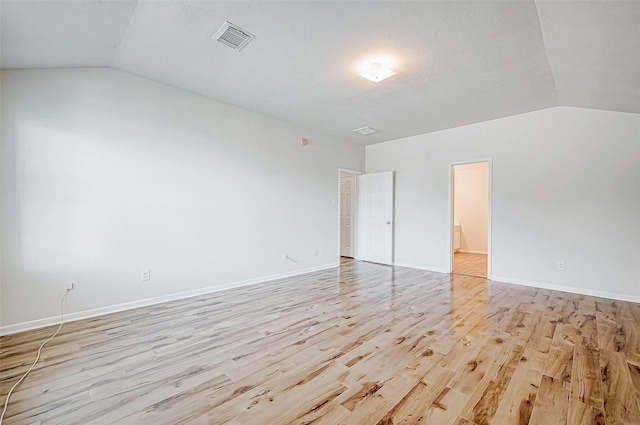 empty room with vaulted ceiling and light hardwood / wood-style flooring