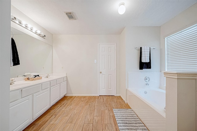 bathroom featuring a textured ceiling, vanity, and a bathtub