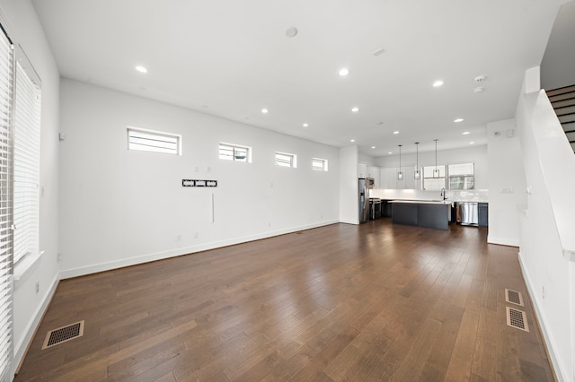 unfurnished living room with dark hardwood / wood-style floors, a healthy amount of sunlight, and sink