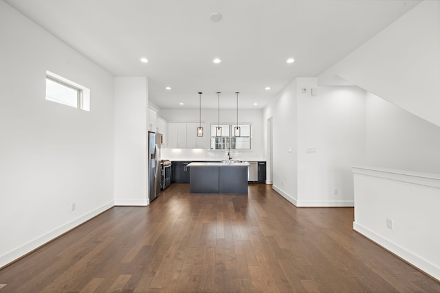 kitchen with stainless steel appliances, pendant lighting, white cabinets, a kitchen island, and plenty of natural light