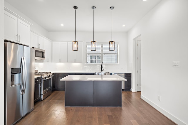 kitchen featuring sink, decorative light fixtures, a kitchen island, white cabinetry, and stainless steel appliances