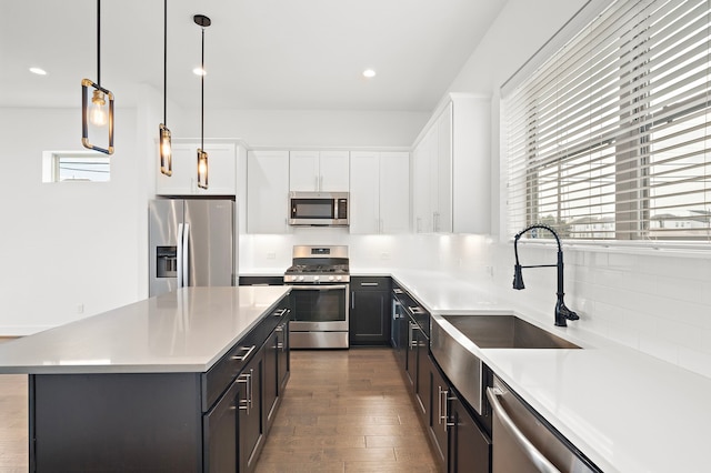 kitchen featuring sink, hanging light fixtures, appliances with stainless steel finishes, white cabinetry, and wood-type flooring