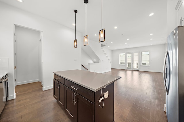 kitchen featuring dark hardwood / wood-style flooring, dark brown cabinetry, a center island, stainless steel refrigerator, and hanging light fixtures