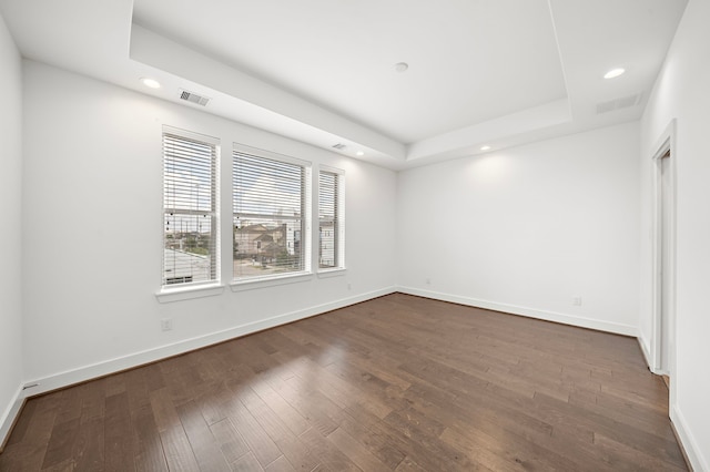 unfurnished bedroom with dark hardwood / wood-style floors and a tray ceiling