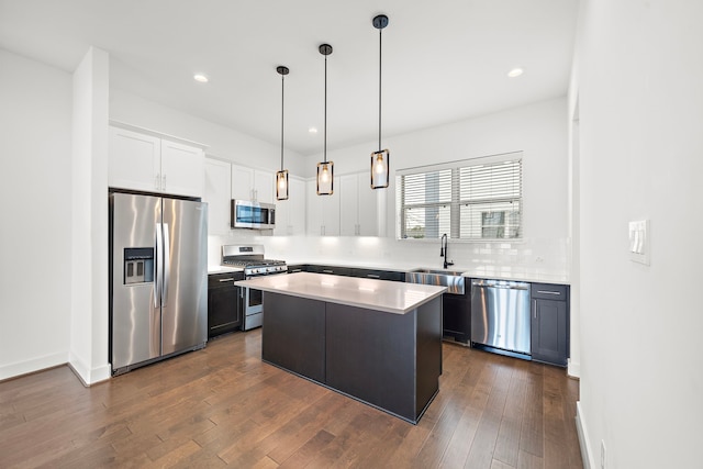 kitchen with sink, decorative light fixtures, a kitchen island, white cabinetry, and stainless steel appliances