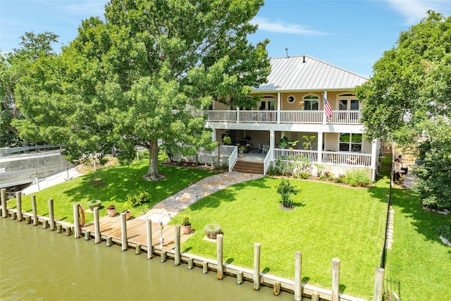 back of property with a water view and a yard