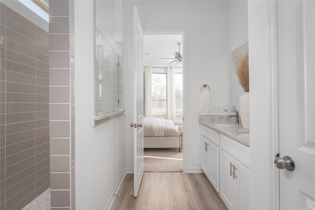 bathroom with tiled shower, vanity, hardwood / wood-style flooring, and ceiling fan