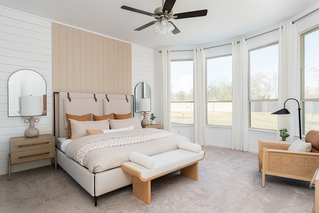 bedroom with light carpet, ceiling fan, and wooden walls