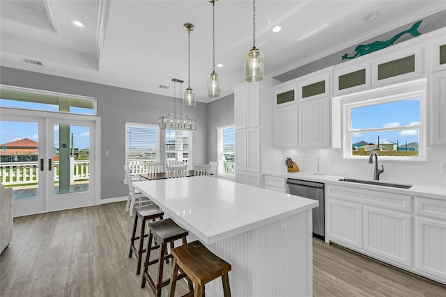 kitchen with white cabinetry, dishwasher, a kitchen island, and pendant lighting