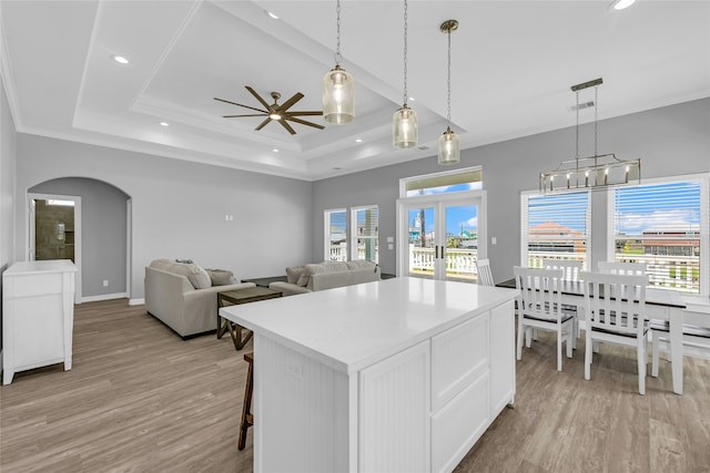 kitchen with ceiling fan, light hardwood / wood-style flooring, white cabinets, and hanging light fixtures