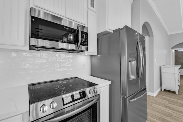 kitchen with light stone counters, white cabinetry, crown molding, and appliances with stainless steel finishes