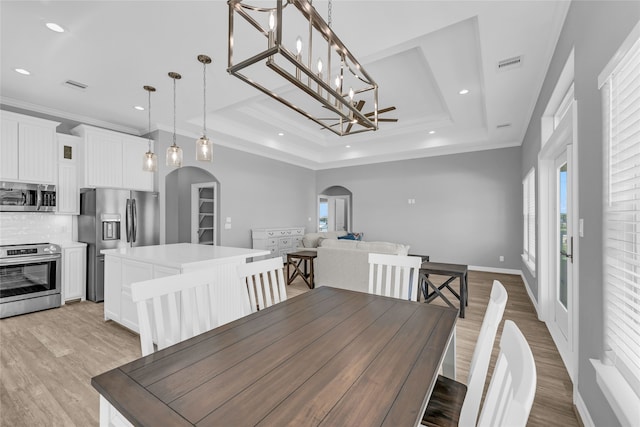 dining space featuring a tray ceiling, crown molding, and light hardwood / wood-style floors