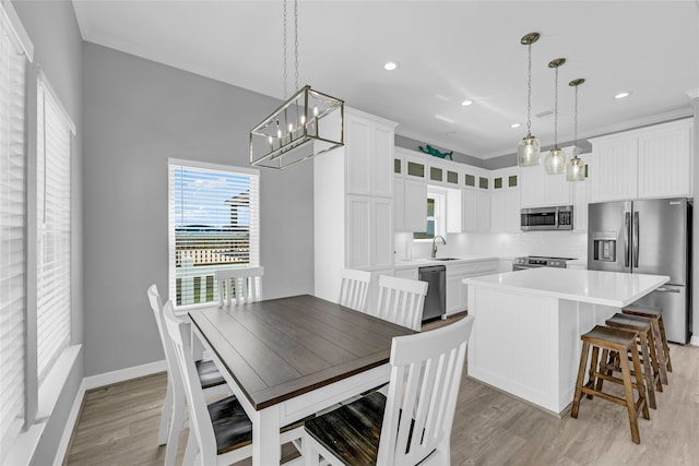 dining area with ornamental molding, sink, and light hardwood / wood-style flooring